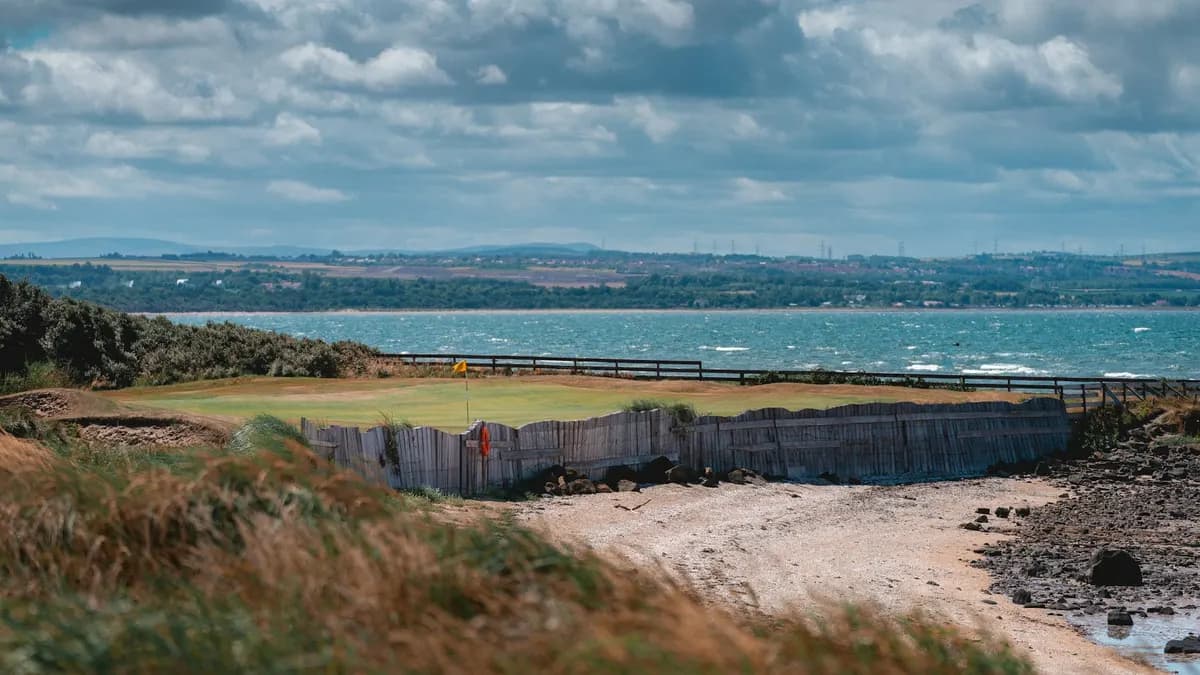 A links golf green beside the sea under a cloudy sky