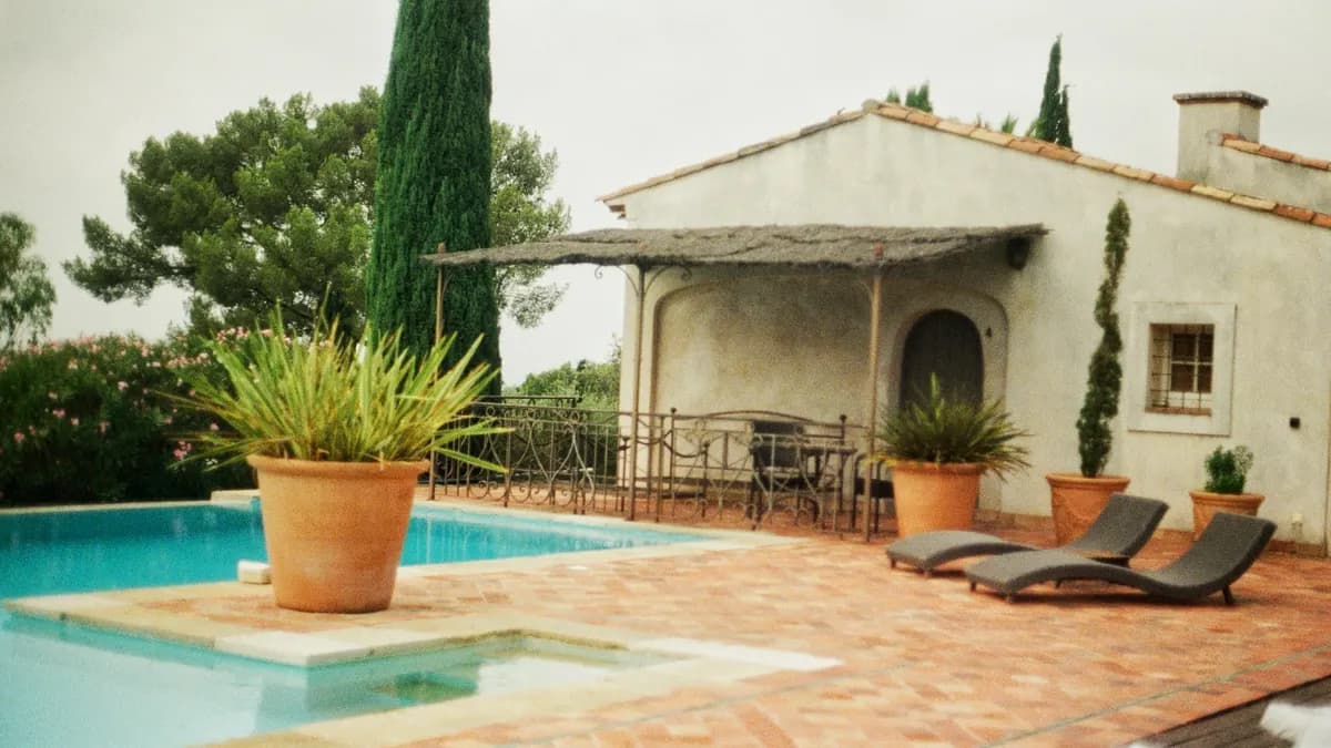 A villa terrace with a swimming pool, terracotta tiles and potted plants
