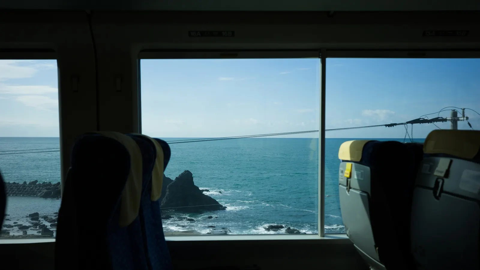The sea and a rocky shore seen through the window of a train carriage